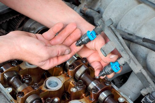 Car mechanic fixing fuel injector at  two camshaft gasoline engine