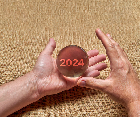 Hands holding a crystal ball, envisioning the future of the year 2024