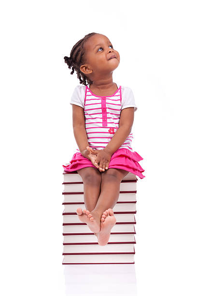 afro-américaine petite fille assise dans une pile de livres - sitting isolated child beautiful photos et images de collection
