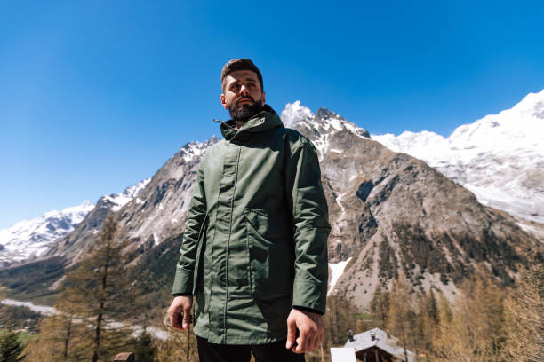 handsome man looking away while hiking in forest and mountains. bearded person wear green warm clothing and enjoying nature outdoors. lifestyle photo with nice real people. - real people beautiful outdoors selective focus imagens e fotografias de stock