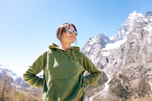 Woman enjoying hiking in the mountains, lifestyle photography on the nature outdoors. Sports photo, climbing concept picture. Person wear sunglasses and warm clothing.