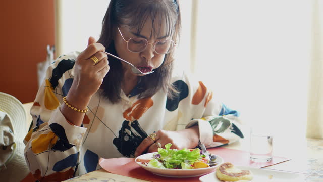 Asian elderly people eating salad vegetables at brunch table.