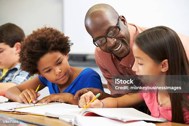 Photo libre de droit de Enseignant Aidant Élèves Étudient Au Bureau En Salle De Classe banque d'images et plus d'images libres de droit de Enseignant