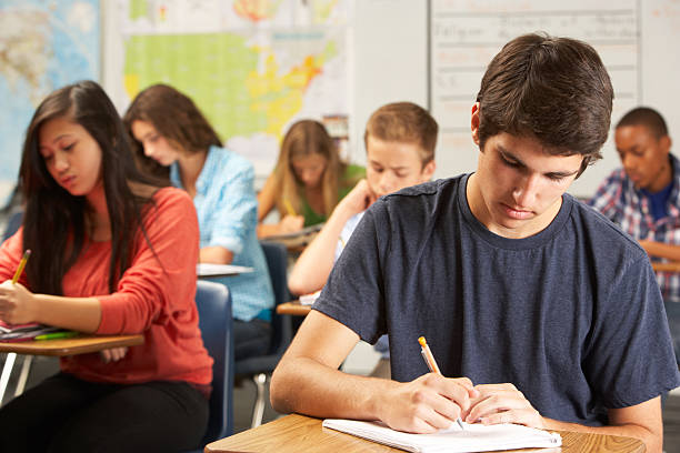 istock Male student writing in a notebook at a desk in a classroom 178472112