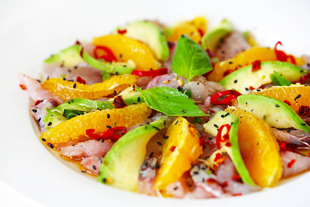 Raw fish salad carpaccio with avocado and orange slices stock photo
