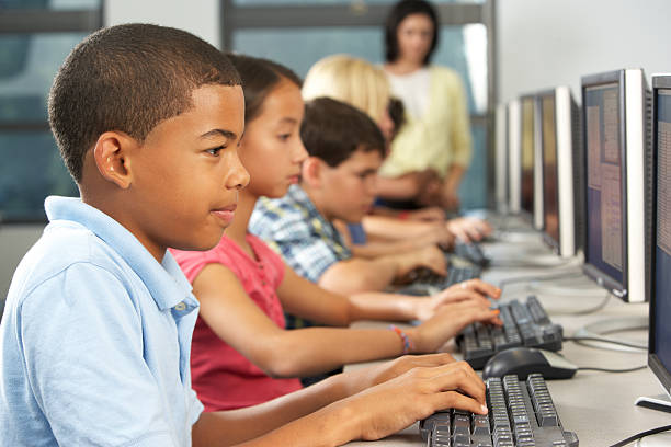 Elementary school students with computers Elementary Students Working At Computers In Classroom Using Keyboard Concentrating people in a row photos stock pictures, royalty-free photos & images