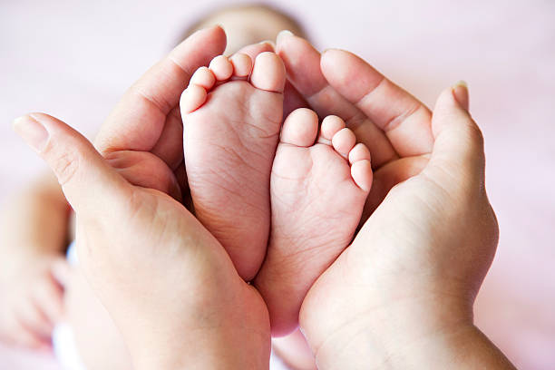 istock mother holding baby feet 178473279