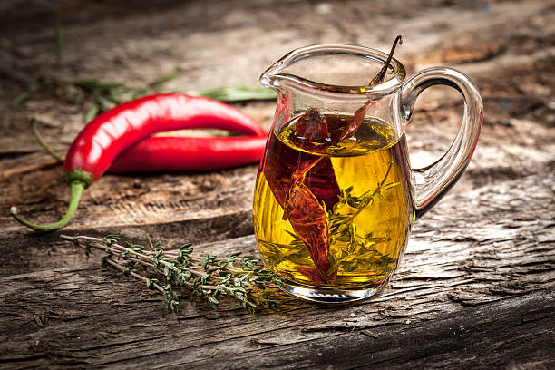 Olive oil with spices and herbs Olive oil with spices and herbs on wooden background shallow depth of field infused oil stock pictures, royalty-free photos & images