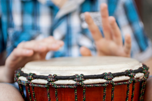 Young man playing on djembe. Shallow depth of field for emphasis on a musical instrument