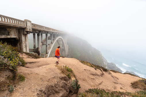 Woman standing on cliff near the Rocky Creek Bridge in Big Sur , California