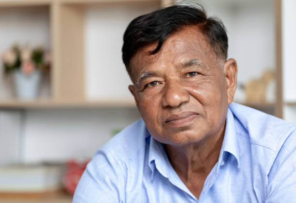 istock Close-up, old man's face, elderly Asian man thinking and looking at camera sit on couch in living room alone. 1784774898