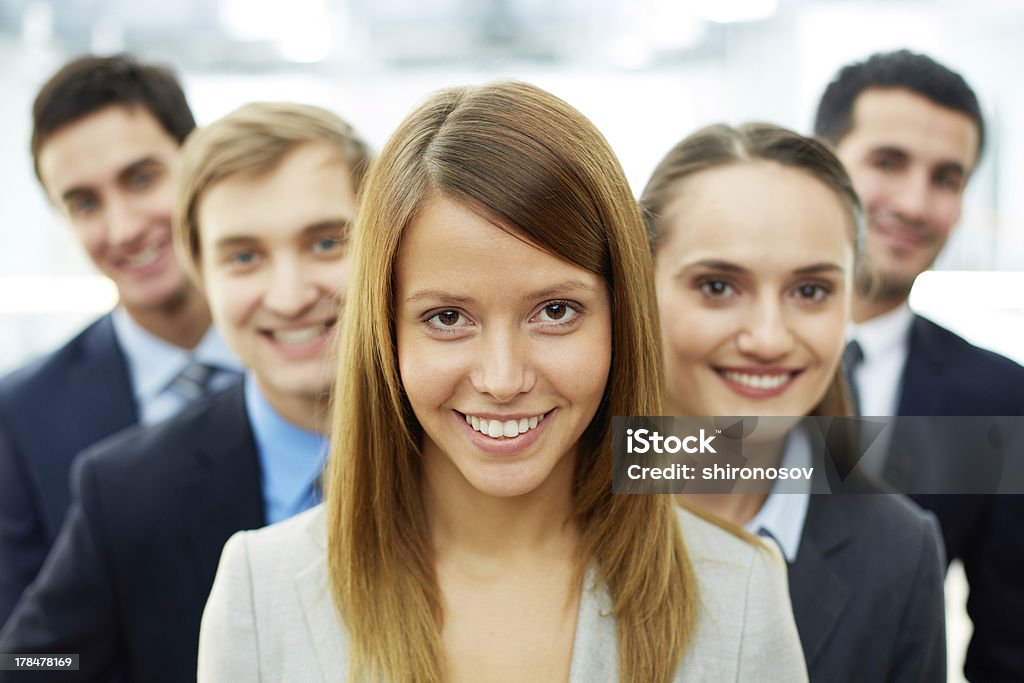 Smart leader Happy businesswoman looking at camera with smart associates behind Adult Stock Photo