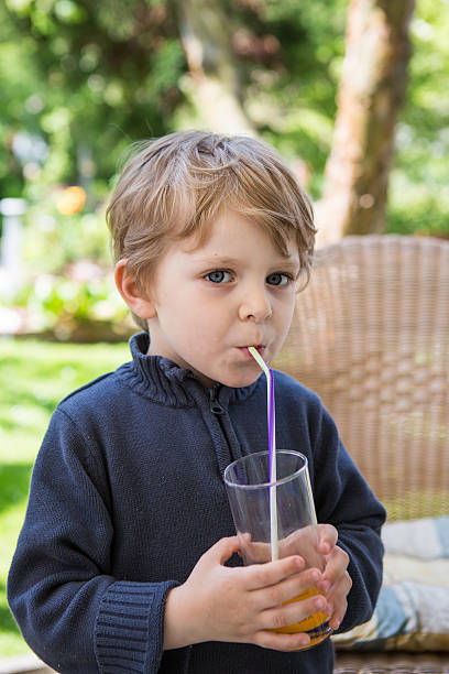 istock Happy little boy drinking orange juice with straw 178479250