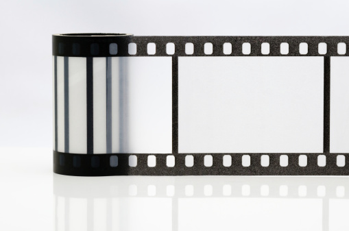 Detail photo of a metal-bodied analog camera and 35mm film taken in a light box with studio light effect