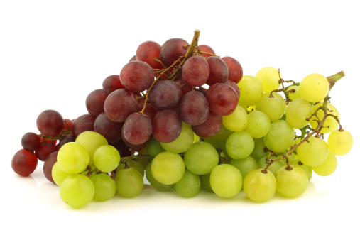 fresh red and white seedless grapes on the vine on a white background