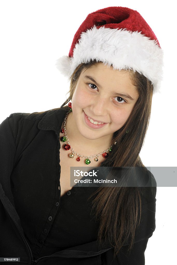 Pretty Christmas Tween Portrait of a pretty preteen in a Santa hat and colorful jingle bell necklace and earrings. 12-13 Years Stock Photo