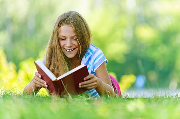 Jeune fille allongée sur l'herbe et la lecture de livre - Photo