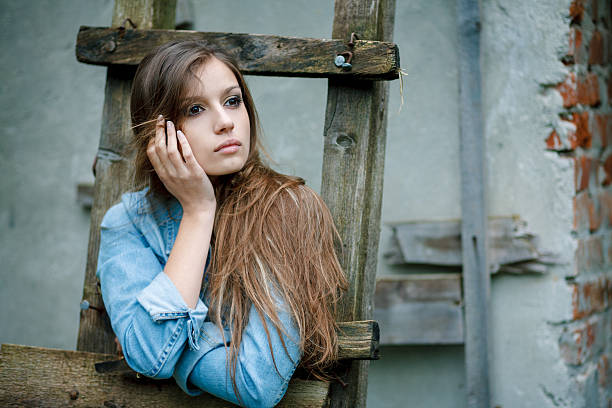 Photo of a teen girl sitting on steps with her hand on her chin.