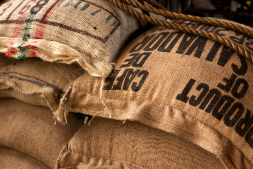 stack of burlap sacks with coffee beans at warehouse
