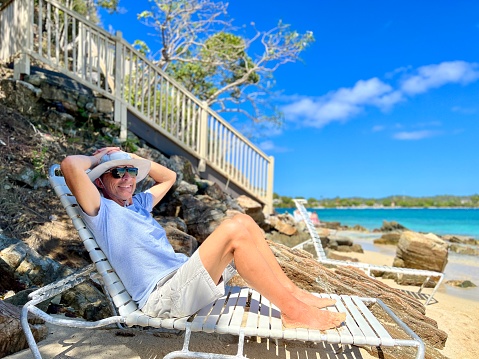 Senior man in sun hat and sunglasses relaxing happily on the us virgin island of St. Thomas island.  Full length