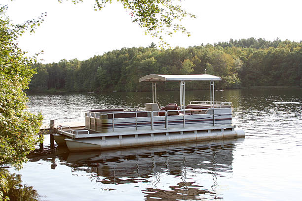 pontoon boat A pontoon boat moored to a dock. pontoon boat stock pictures, royalty-free photos & images