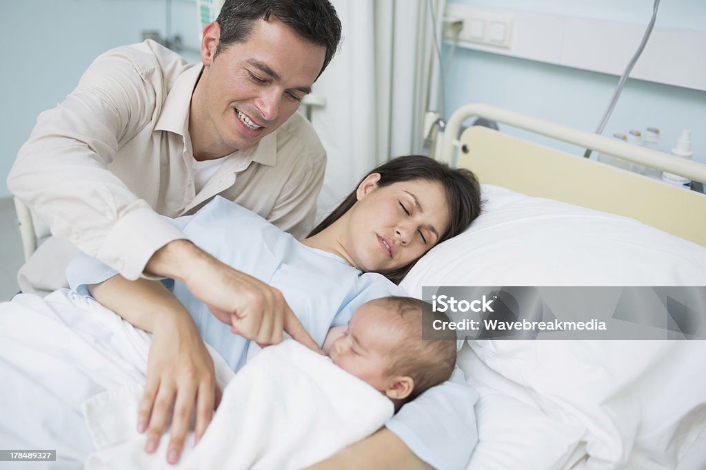 Отец, глядя на его Спящая жена и новорожденного ребенка - Стоковые фото 30-39 лет роялти-фри