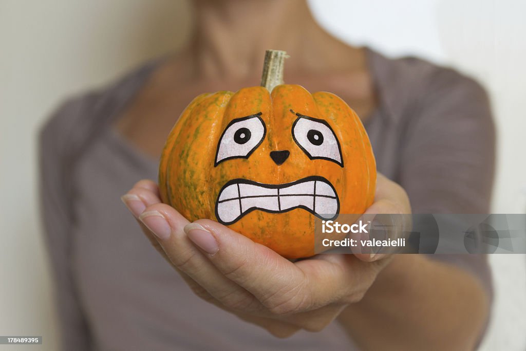 Woman holds in her hand a terrified Halloween pumpkin A woman holds in her hand a terrified Halloween pumpkin Pumpkin Stock Photo