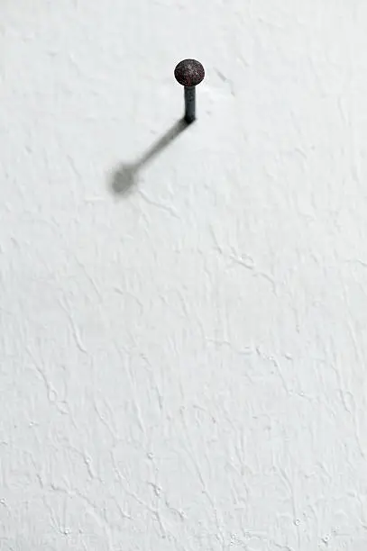 closeup of nail into white wall to frame