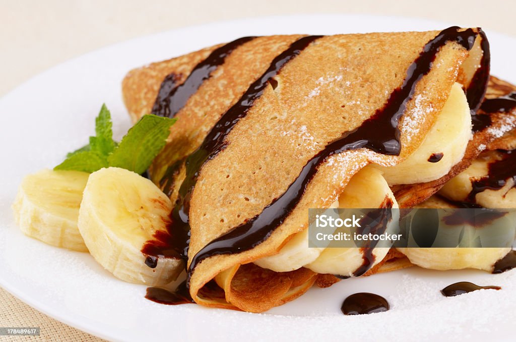 Freshly baked crepes with chocolate sauce and bananas "French style crepes with banana, chocolate sauce and sugar powder" Crêpe - Pancake Stock Photo