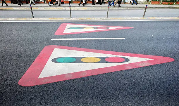 Traffic light signs painted on pavement with pedestrian walking on background