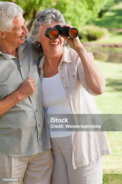 Photo libre de droit de Mari Femme Donne À Travers Des Jumelles Câlins banque d'images et plus d'images libres de droit de Adulte - Adulte, Adulte d'âge mûr, Amour