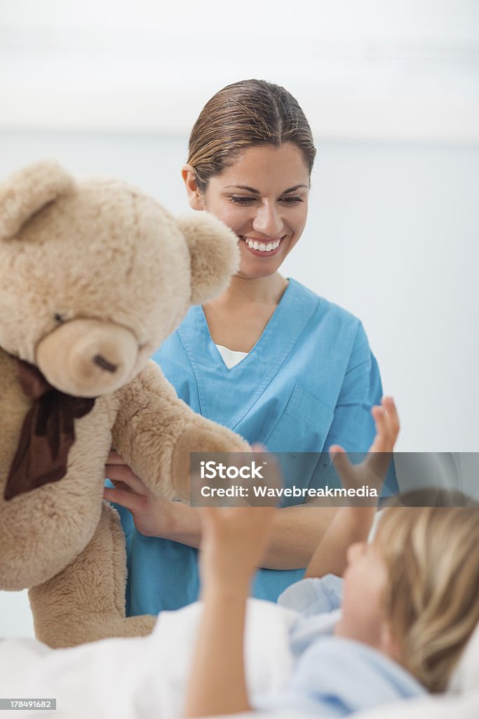 Sorridente enfermeira mostrando Urso de Pelúcia para uma criança - Royalty-free Criança Foto de stock