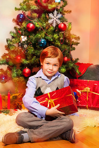 istock Cute boy sitting near Christmas tree 178491724