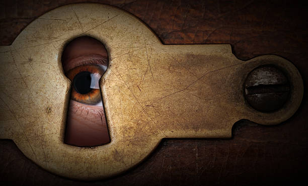 Macro shot of a brown young woman's eye Brown eye looking through a vintage metal keyhole woman spying through a keyhole stock pictures, royalty-free photos & images