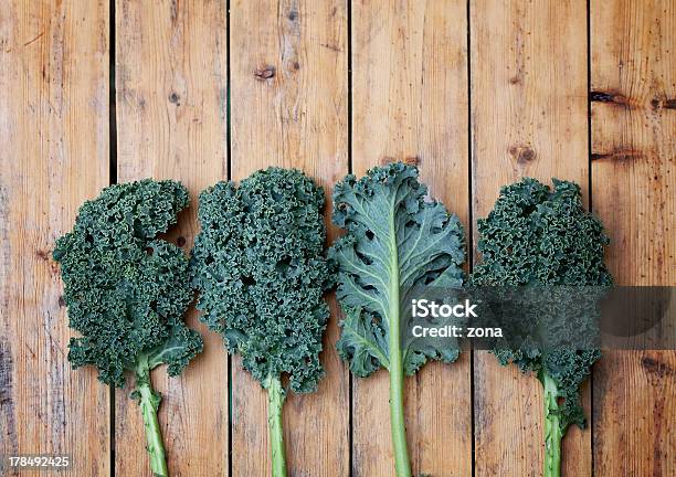 Four Pieces Of Kale One Turned Over On A Wooden Background Stock Photo - Download Image Now