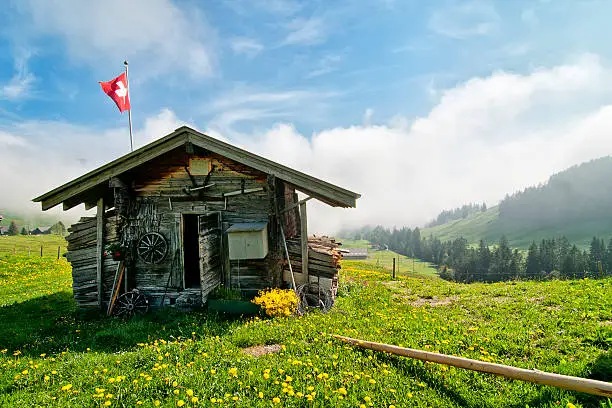 Traditional Swiss wooden hut with flag in the mountains