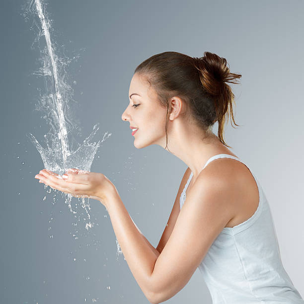 Young woman washing her face and hands with clean water in the morning