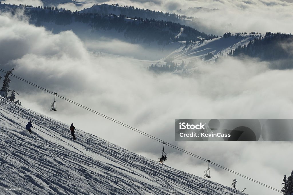 Grand Targhee Powder "A skier and snowboarder find tracked powder snow above the fog on a winter afternoon at Grand Targhee, Wyoming." Fog Stock Photo