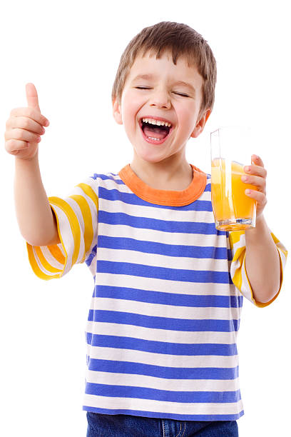 menino sorridente, desfrutando de um copo de suco - isolated on white fun orange food - fotografias e filmes do acervo