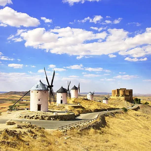 Photo of A row of windmills and a castle in Consuegra, Spain