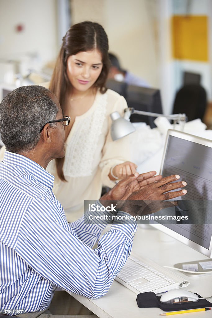 Workers At Desks In Busy Creative Office Workers At Desks In Busy Creative Office Having A Conversation Discussion Stock Photo