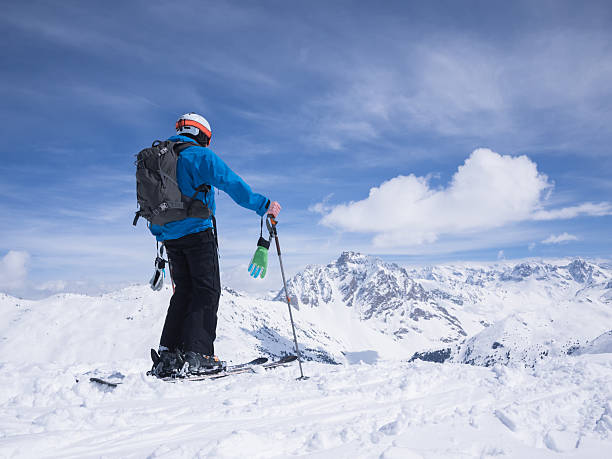 Skier looking out over mountain landscape stock photo