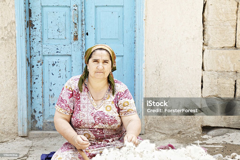 Woman with wool Senior woman with mass of wool sitting outdoors against door Active Lifestyle Stock Photo