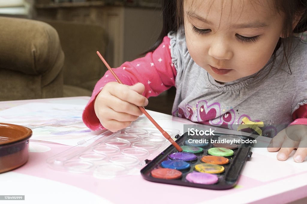 Piccola ragazza asiatica apprendimento di vernice con acquerelli a casa - Foto stock royalty-free di Bambino di età prescolare