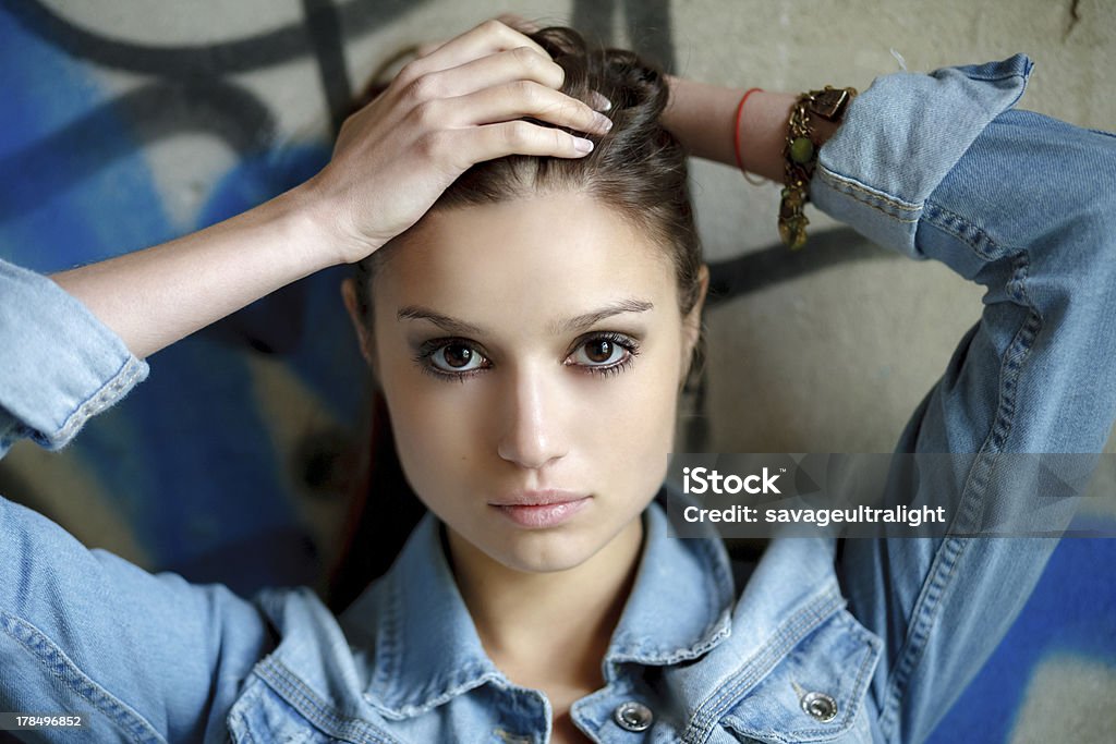 young female outdoors closeup portrait of young female holding hair with her hands  wearing a jean jacket looking at camera Adult Stock Photo