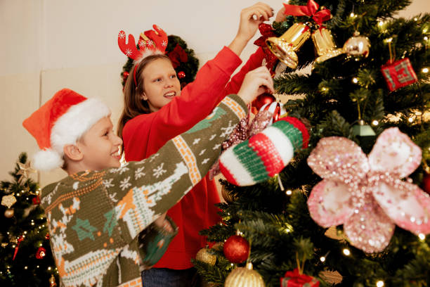 istock girl and boy decorating Christmas tree at home 1784985765