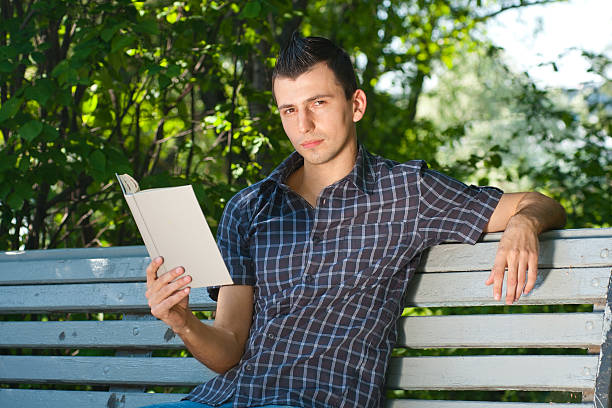 istock Young man reading book outdoors 178498645