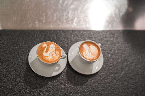 The bar counter becomes a focal point of admiration with the exquisite latte art showcased on coffee cups, elevating the ambiance of the coffee house to a new level.