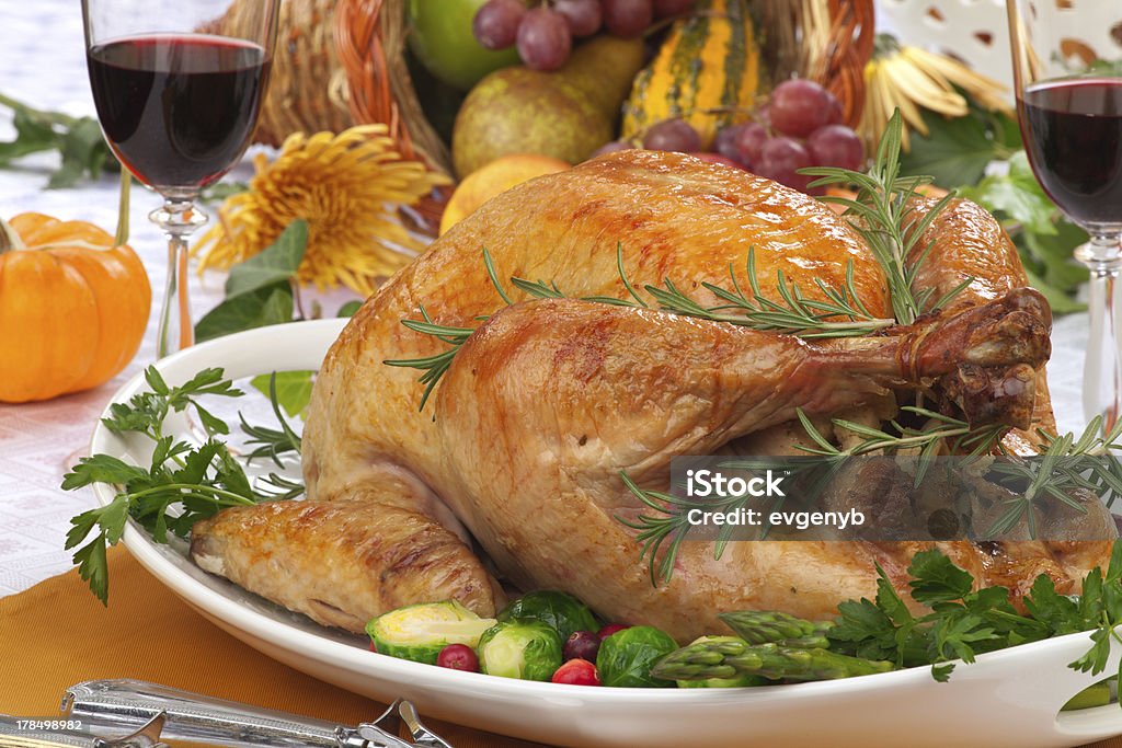 Fall festival roast turkey Garnished roasted turkey on fall festival decorated table with horn of plenty and red wine Brussels Sprout Stock Photo