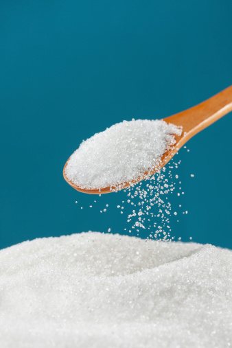 Sugar pouring from a spoon to a pile
